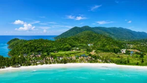 Panoramic aerial view of Blue Haven Bay's private beach, tropical coastline, and surrounding mountains on Koh Chang
