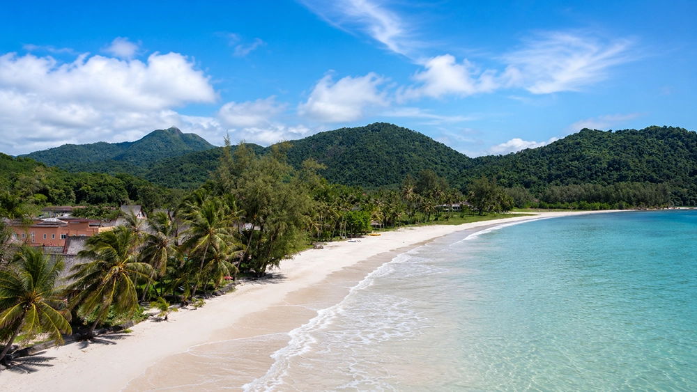Private white sand beach at Blue Haven Bay Koh Chang with tropical coastline, palm trees, and calm turquoise water